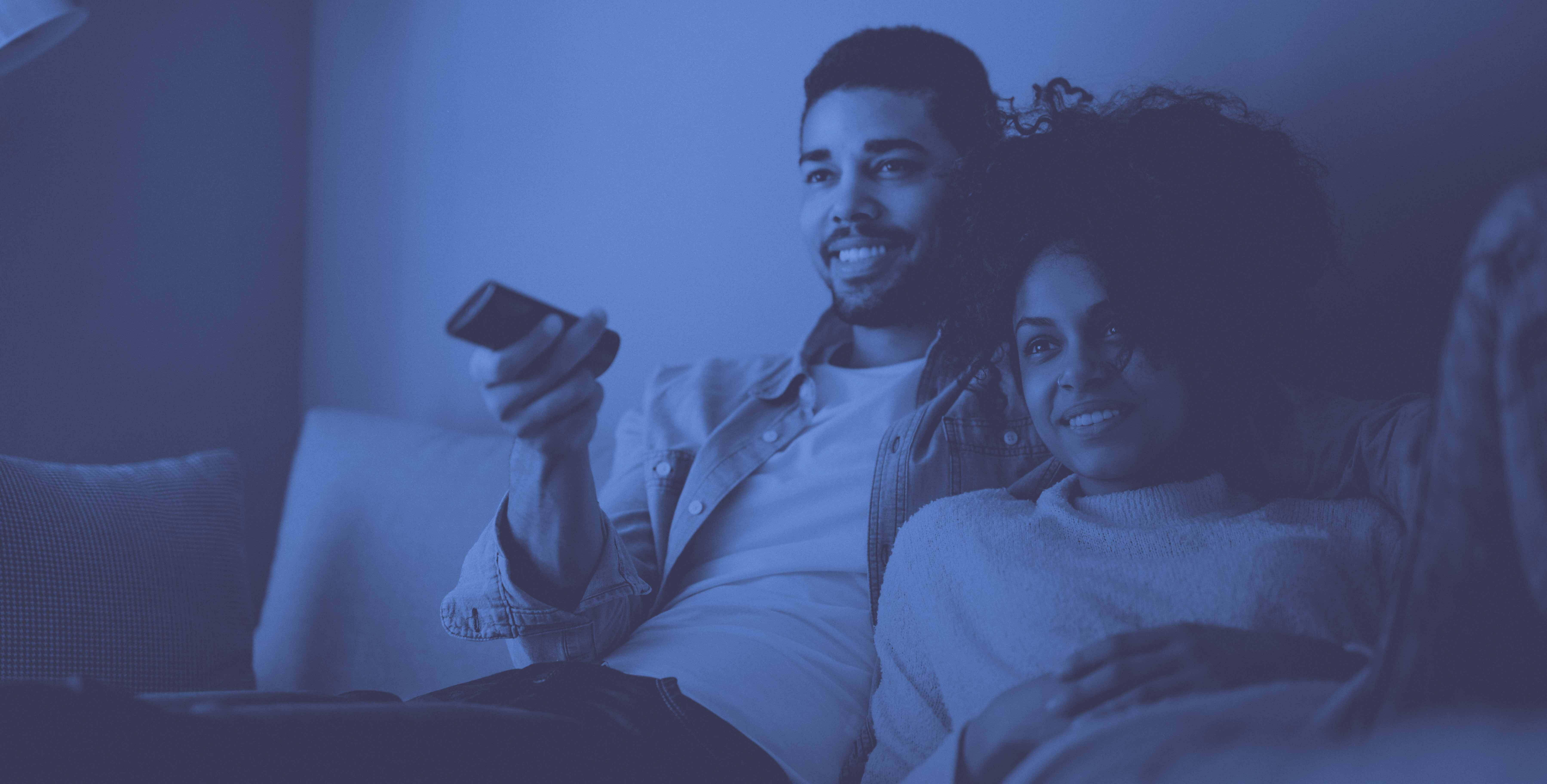man and woman sitting on couch with remote watching TV